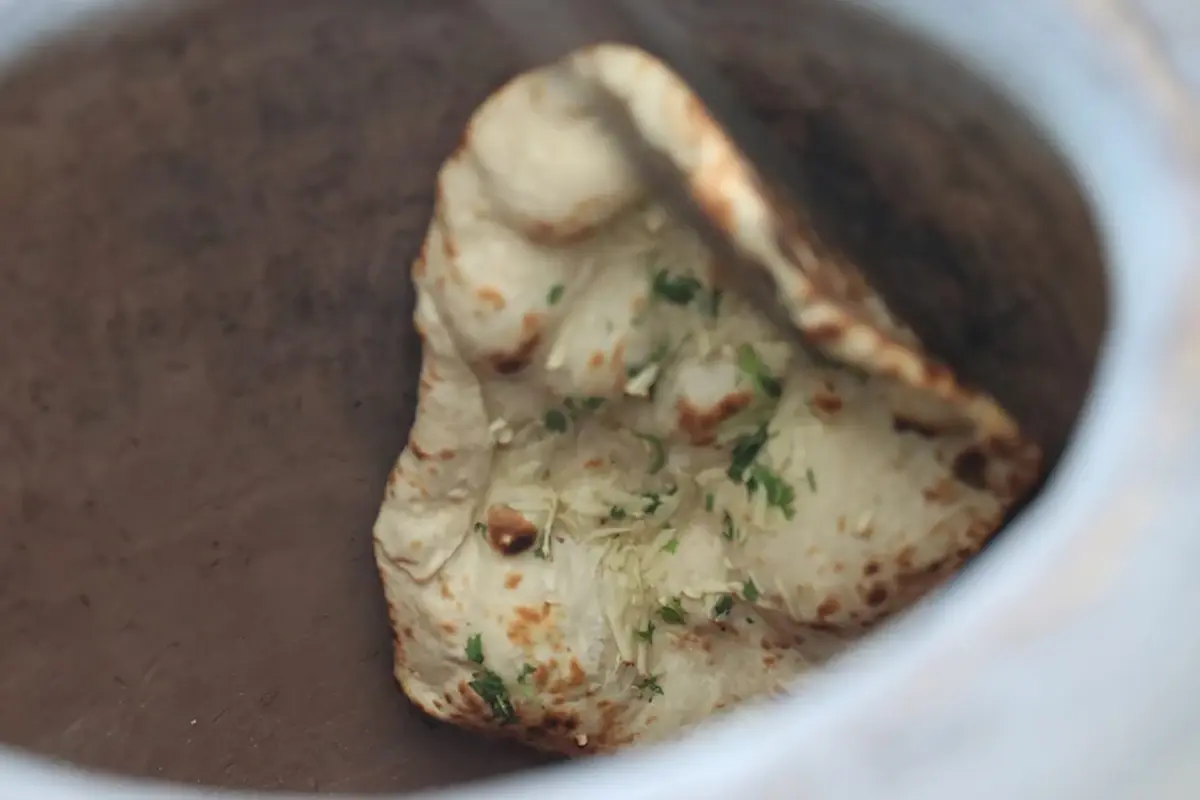 Garlic naan baking on the clay wall of a GULATI tandoor