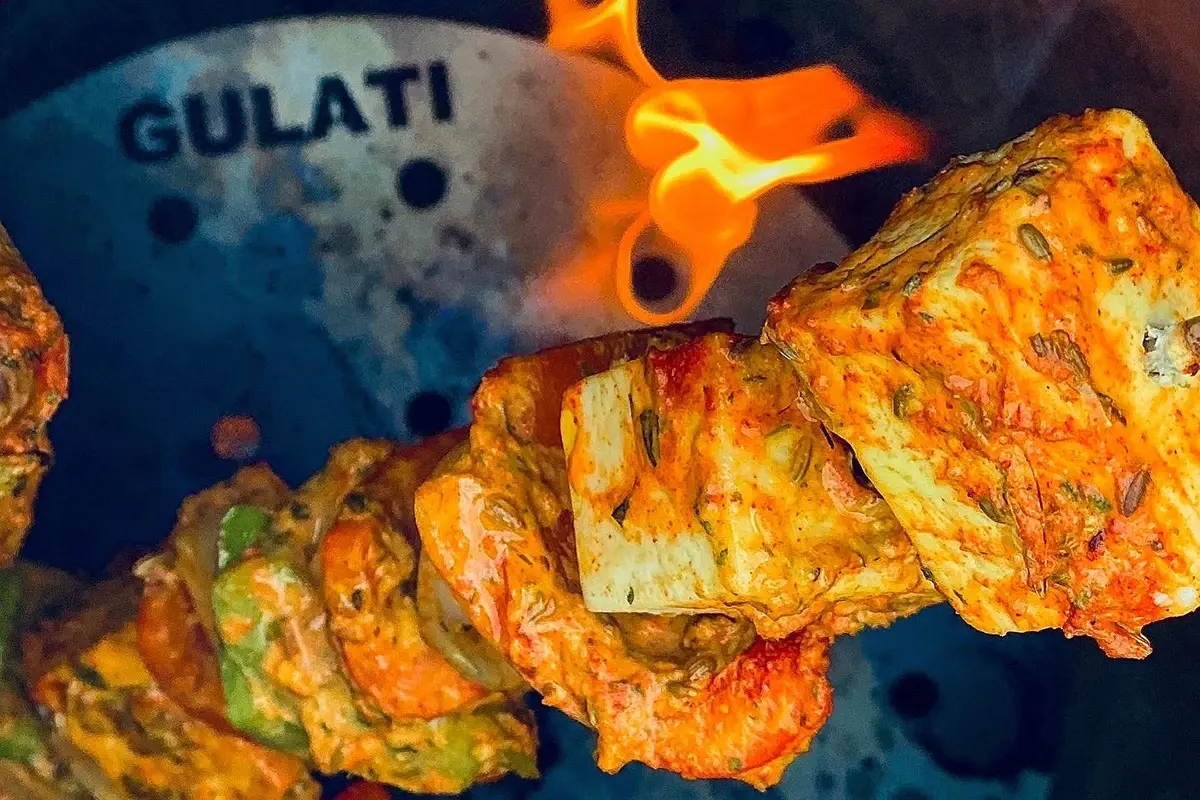 Paneer and vegetable tikka skewer over a GULATI TandoorDISC
